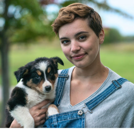 Pet Food & SuppliesYoung woman in overalls holding a puppy