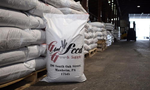 Stacks of feed bags with a visible G And G Feed & Supply brand logo in a warehouse setting